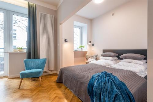 a bedroom with a large bed and a blue chair at Plater & Poznanska Serviced Apartments in Warsaw