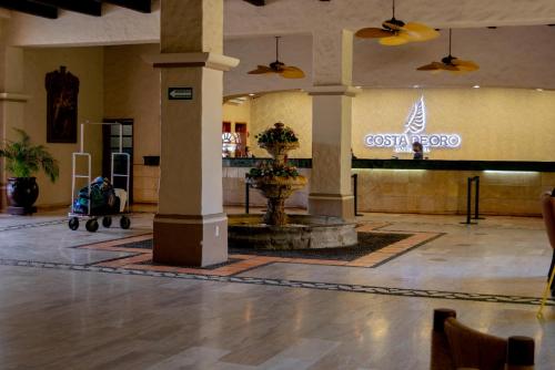 a lobby with a fountain in the middle of a building at Costa de Oro Beach Hotel in Mazatlán