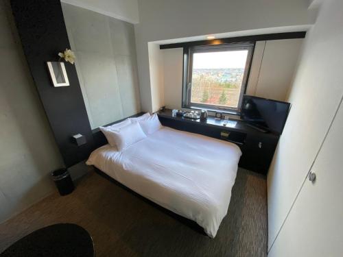 ein Schlafzimmer mit einem weißen Bett und einem Fenster in der Unterkunft ＦＵＲＡＮＯ ＮＡＴＵＬＵＸ ＨＯＴＥＬ - Vacation STAY 68188v in Furano