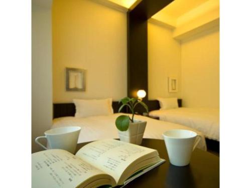 an open book on a table with two beds at ＦＵＲＡＮＯ ＮＡＴＵＬＵＸ ＨＯＴＥＬ - Vacation STAY 68196v in Furano