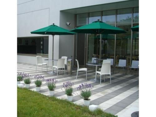 a patio with a table and chairs and umbrellas at ＦＵＲＡＮＯ ＮＡＴＵＬＵＸ ＨＯＴＥＬ - Vacation STAY 68196v in Furano