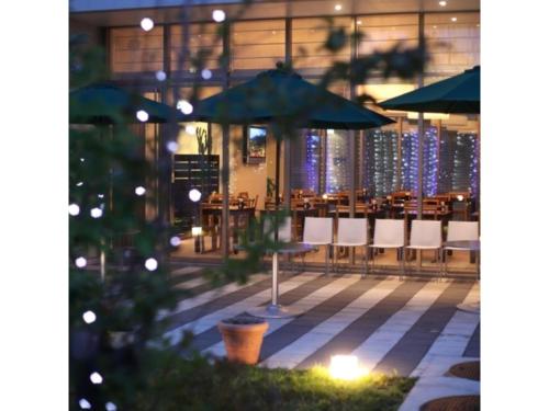 a restaurant with tables and umbrellas at night at ＦＵＲＡＮＯ ＮＡＴＵＬＵＸ ＨＯＴＥＬ - Vacation STAY 68187v in Furano