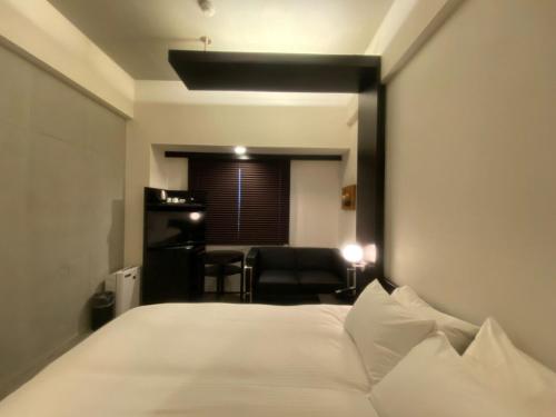 um quarto com uma grande cama branca e uma cadeira em ＦＵＲＡＮＯ ＮＡＴＵＬＵＸ ＨＯＴＥＬ - Vacation STAY 68187v em Furano