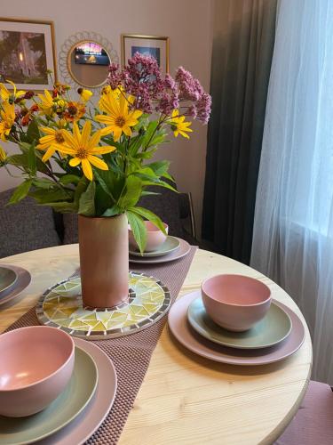 a table with plates and a vase of flowers on it at Pērles in Līgatne