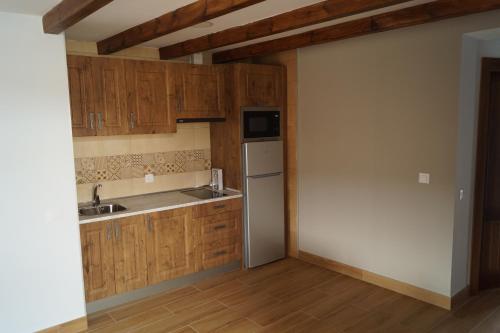 eine Küche mit Holzschränken, einer Spüle und einem Kühlschrank in der Unterkunft Puente Viejo de Buitrago CASA ROBLE in Buitrago del Lozoya