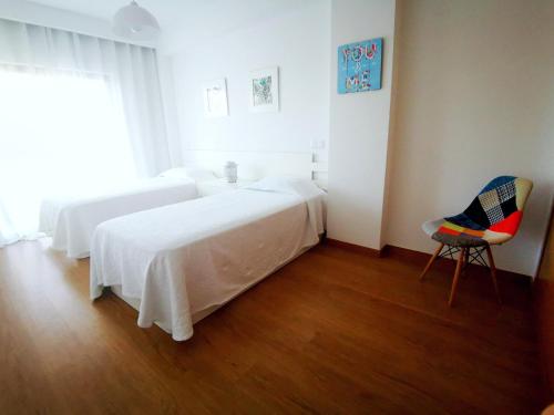 a white bedroom with a bed and a chair at Terraços do Rio in Portimão