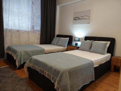two beds in a hotel room with a window at Monteverde Ski Lift Apartment Bansko in Bansko