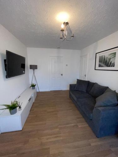 Una sala de estar con un sofá y un televisor. en Modern 2 bed house Cannock Driveway for 2 vehicles Perfect for contractors Business Travellers Short Stays Close to M6 M54 i54 A5 A38 McArthur Glen Designer Outlet, en Cannock