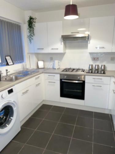 a white kitchen with a stove and a washing machine at Lovely 2 bed house Cannock Driveway for 2 vehicles Perfect for contractors Business Travellers Short Stays Close to M54 M6 i54 A38 A5 McArthur Glen Designer Outlet in Cannock