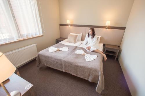 a woman sitting on a bed in a hotel room at Goda Hotel & Spa in Druskininkai