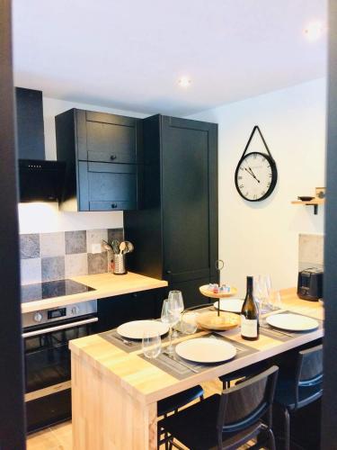 une cuisine avec une table, des chaises et une horloge murale dans l'établissement CÀLM, Cocon À La Mer, Blériot-Plage, à Sangatte
