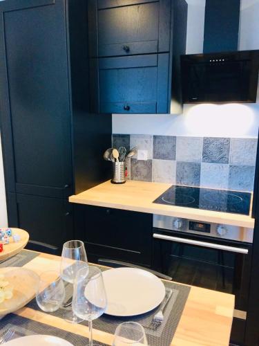 une cuisine avec des placards noirs et des plaques blanches sur une table dans l'établissement CÀLM, Cocon À La Mer, Blériot-Plage, à Sangatte