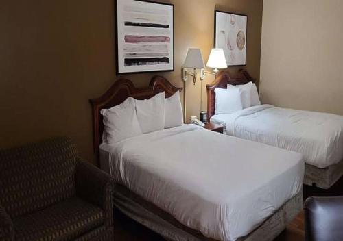 a hotel room with two beds and a chair at Auburn Place Hotel & Suites Cape Girardeau in Cape Girardeau