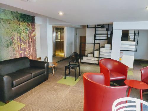 a living room with a black couch and red chairs at Hotel Viaggio Teleport City Suites in Bogotá