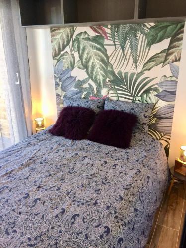 - un lit avec une couette violette et un mur orné de plantes dans l'établissement CÀLM, Cocon À La Mer, Blériot-Plage, à Sangatte