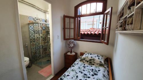 a bathroom with a shower and a bed and a window at Casa Vermelha in Rio de Janeiro