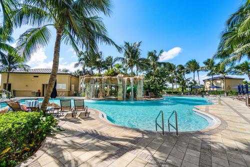 a swimming pool with palm trees in a resort at Palm Beach Singer Island Resort & Spa Luxury Suites in Riviera Beach