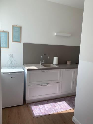 uma cozinha branca com um lavatório e um frigorífico em Al viale - a Negrar nel cuore della Valpolicella em Negrar