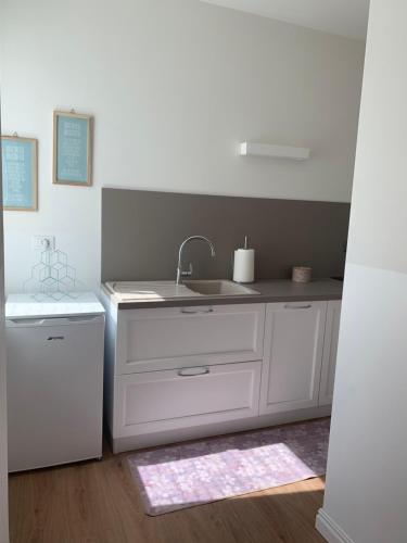a white kitchen with a sink and a refrigerator at Al viale - a Negrar nel cuore della Valpolicella in Negrar