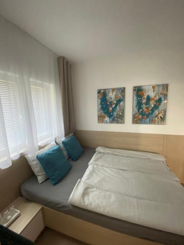 Cama en habitación con 2 almohadas azules en MAXIM Apartments, en Harkány