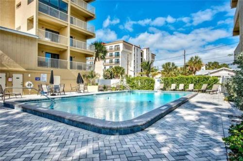 a swimming pool with chairs and a building at Beach condo in the heart of Clearwater beach in Clearwater Beach