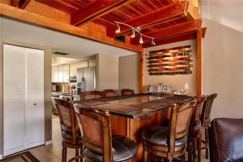 a kitchen with a large wooden bar with leather chairs at Beach condo in the heart of Clearwater beach in Clearwater Beach