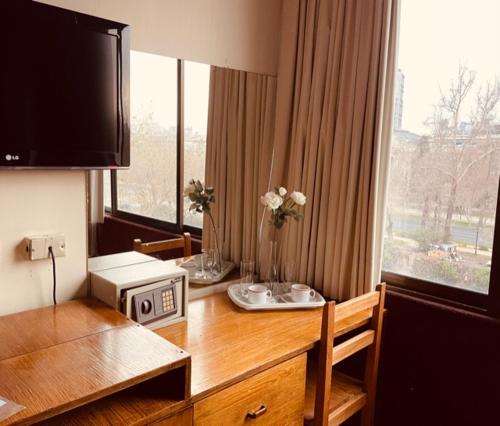 a room with a desk with a microwave and a window at Tremo Santa María 281 in Santiago