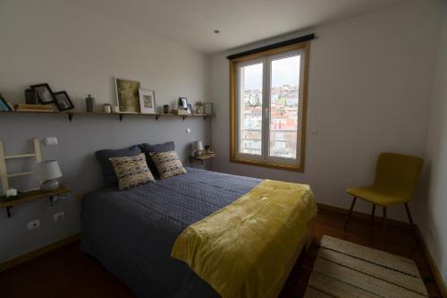 a bedroom with a bed and a window and a chair at Avenida Central - Coimbra Accommodation in Coimbra