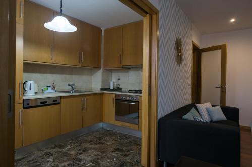 a kitchen with wooden cabinets and a couch in a room at Avenida Central - Coimbra Accommodation in Coimbra
