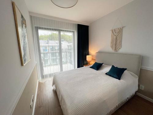 une chambre avec un lit avec des oreillers bleus et une fenêtre dans l'établissement Nadmorska ucieczka Niechorze - Niechorze Seaside Getaway - Rezydencja Niechorze, à Niechorze