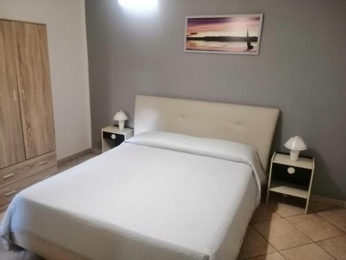 een slaapkamer met een wit bed en 2 nachtkastjes bij Villa Aurora Per Vacanze in Palermo
