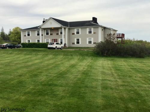a large white house with a car parked in the yard at Rollo Bay Inn in Souris