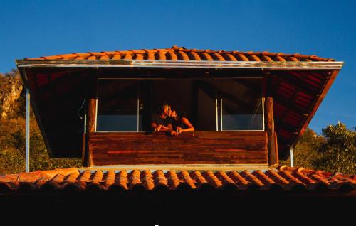 a woman sitting in the window of a house at Pousada Varanda da Serra in Cavalcante
