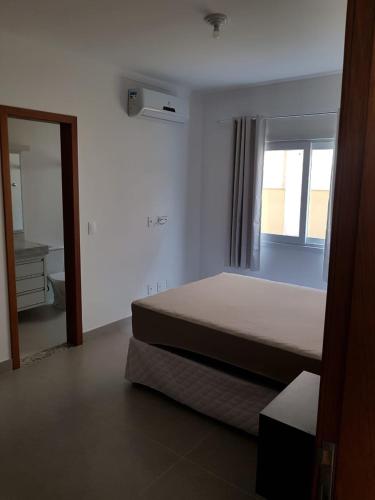 Schlafzimmer mit einem Bett, einem Fenster und einem Spiegel in der Unterkunft Apartamento Beira-Mar, Paraíso dos Pataxós. in Porto Seguro