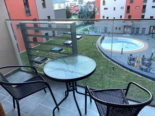 a table and chairs on a balcony with a pool at Apartment Family Besenova - free pool in Bešeňová