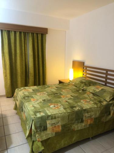 ein Schlafzimmer mit einem Bett mit einer grünen Bettdecke in der Unterkunft Hotel Apartamento Giardino - Rio Quente 433-P in Rio Quente