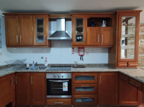 a kitchen with wooden cabinets and a stove top oven at Zimão Garden House in Vila Real