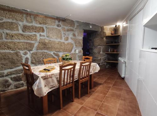 a dining room with a table and chairs and a stone wall at Zimão Garden House in Vila Real