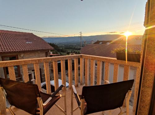 a balcony with two chairs and a view of a city at Zimão Garden House in Vila Real