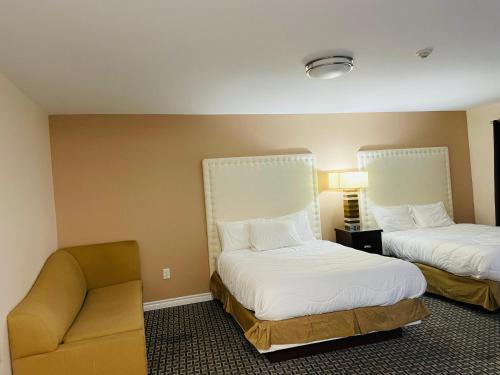um quarto de hotel com duas camas e uma cadeira em Falls Lodge by the Falls (Formerly Knights Inn) em Cataratas do Niágara