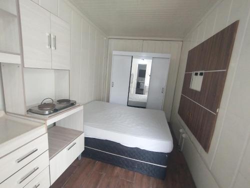 een kleine witte kamer met een bed en kasten bij Marco Zero Containers 2 in Balneário Camboriú