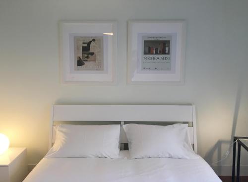 a bedroom with a white bed with two pictures on the wall at Room Atalaia - Bairro Alto in Lisbon