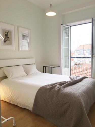 a white bedroom with a large bed and a window at Room Atalaia - Bairro Alto in Lisbon