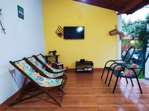a living room with chairs and a tv on a yellow wall at Pousada Águas da Chapada in Carolina