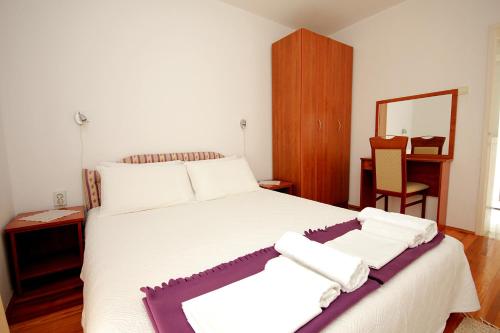 a bedroom with a large white bed with towels on it at Guesthouse Drašković in Petrovac na Moru