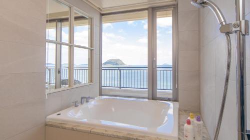 a white bathroom with a tub and a window at Karatsu Seaside Hotel in Karatsu