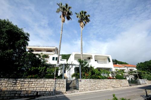 two palm trees in front of a white building at Guesthouse Drašković in Petrovac na Moru