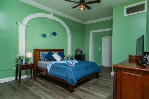 a bedroom with green walls and a bed with a blue blanket at Victoria House in Frederiksted