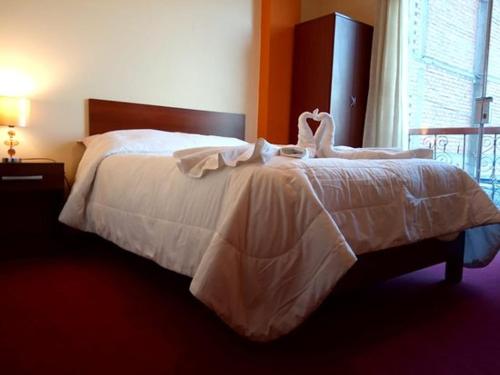 a bedroom with a bed with white sheets and a window at Marlon's House Puno-Peru in Puno