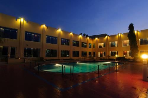 a large building with a swimming pool at night at Ramee Dream Resort in Seeb